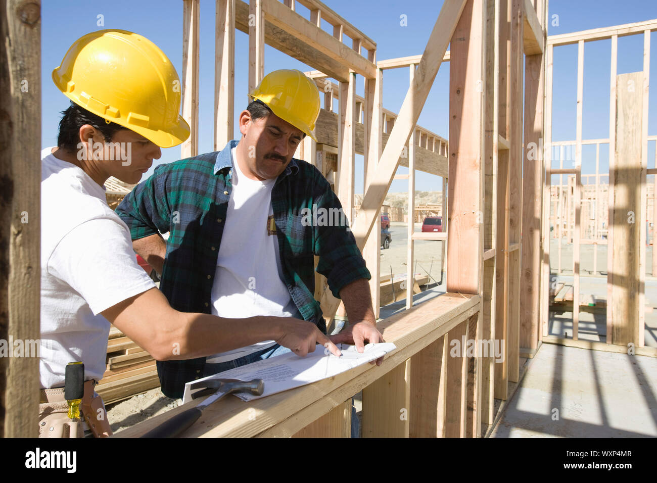 Construction workers reading blueprint on building site Stock Photo Alamy