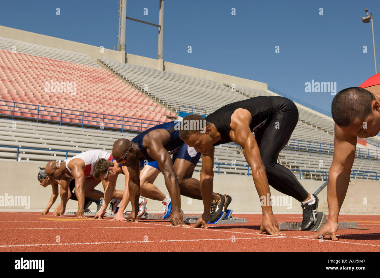 Runners waiting in starting blocks on track Stock Photo - Alamy