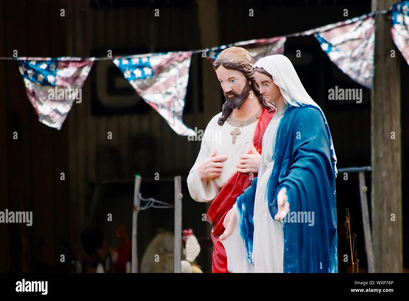 Kitsch statues of jesus and Mary in front of an American Flag banner Stock Photo