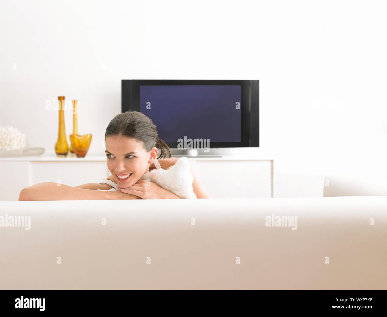 Smiling young woman relaxing on sofa in modern living room Stock Photo ...