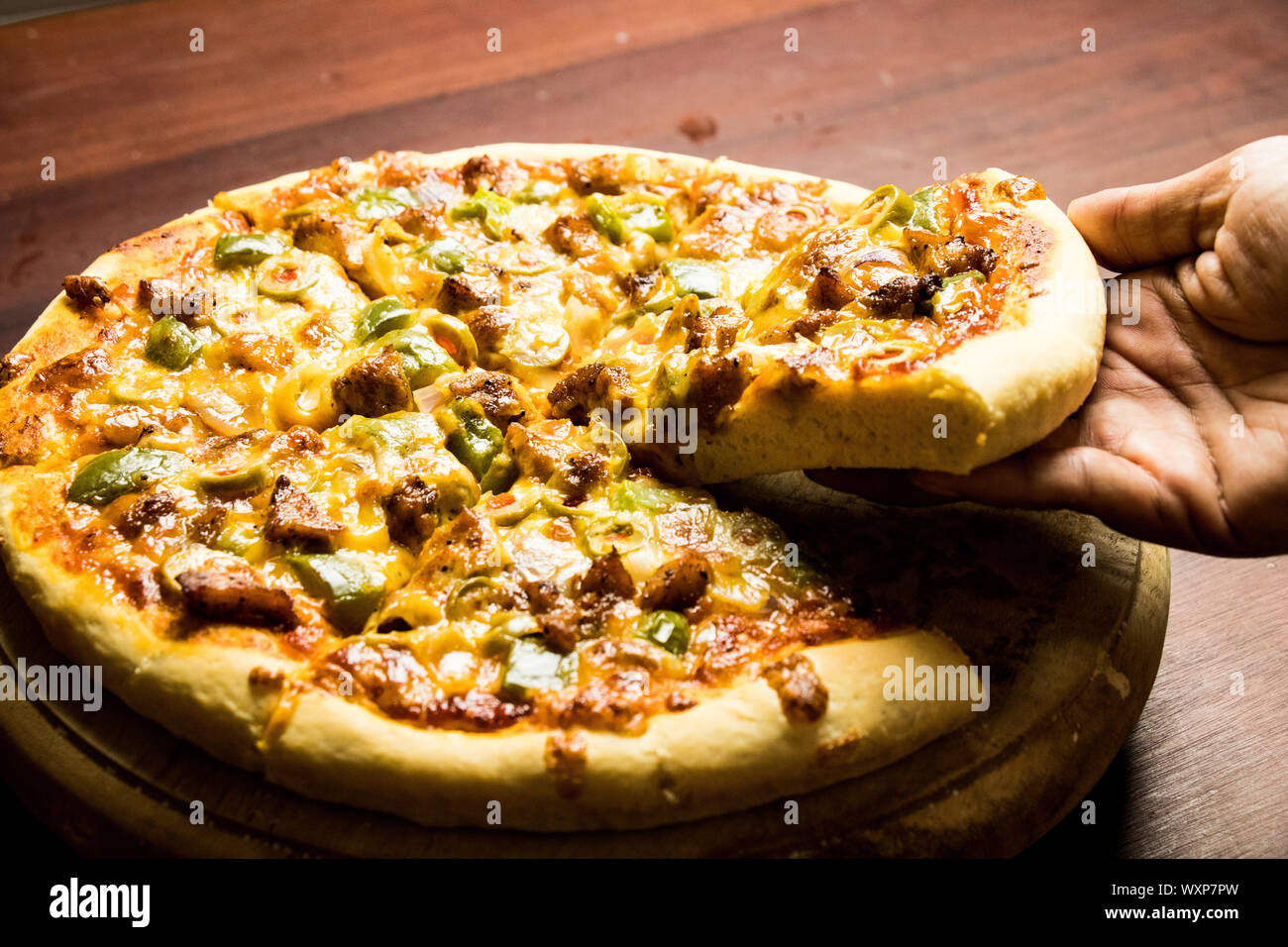 Pan Pizza Slice Take From Hand Side View With Dark Brown Wood Stock Photo Alamy