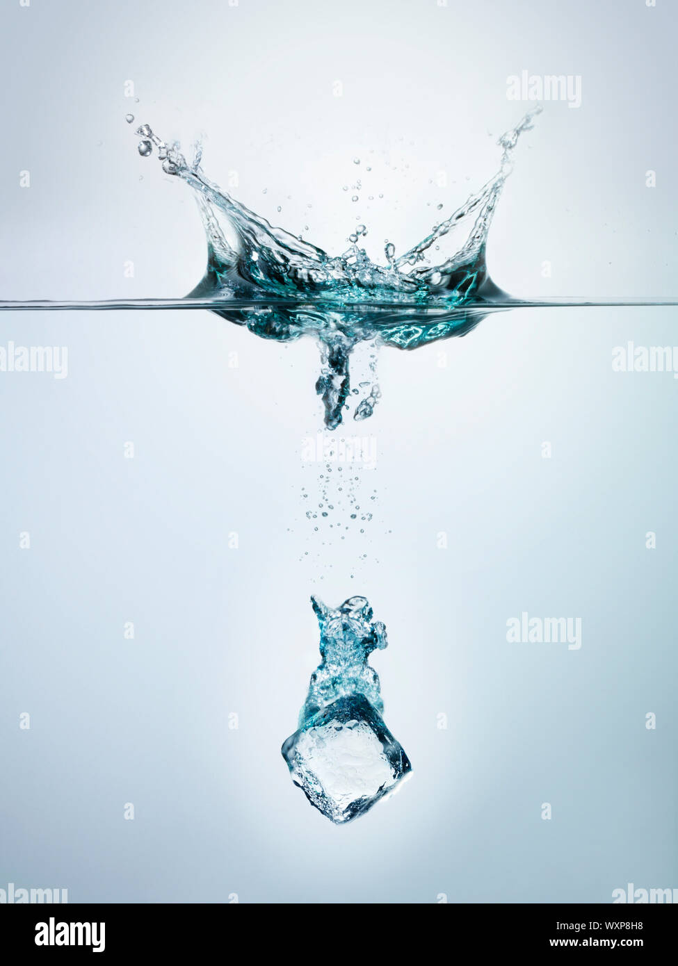 Ice cube splashing into clear water surface view Stock Photo - Alamy