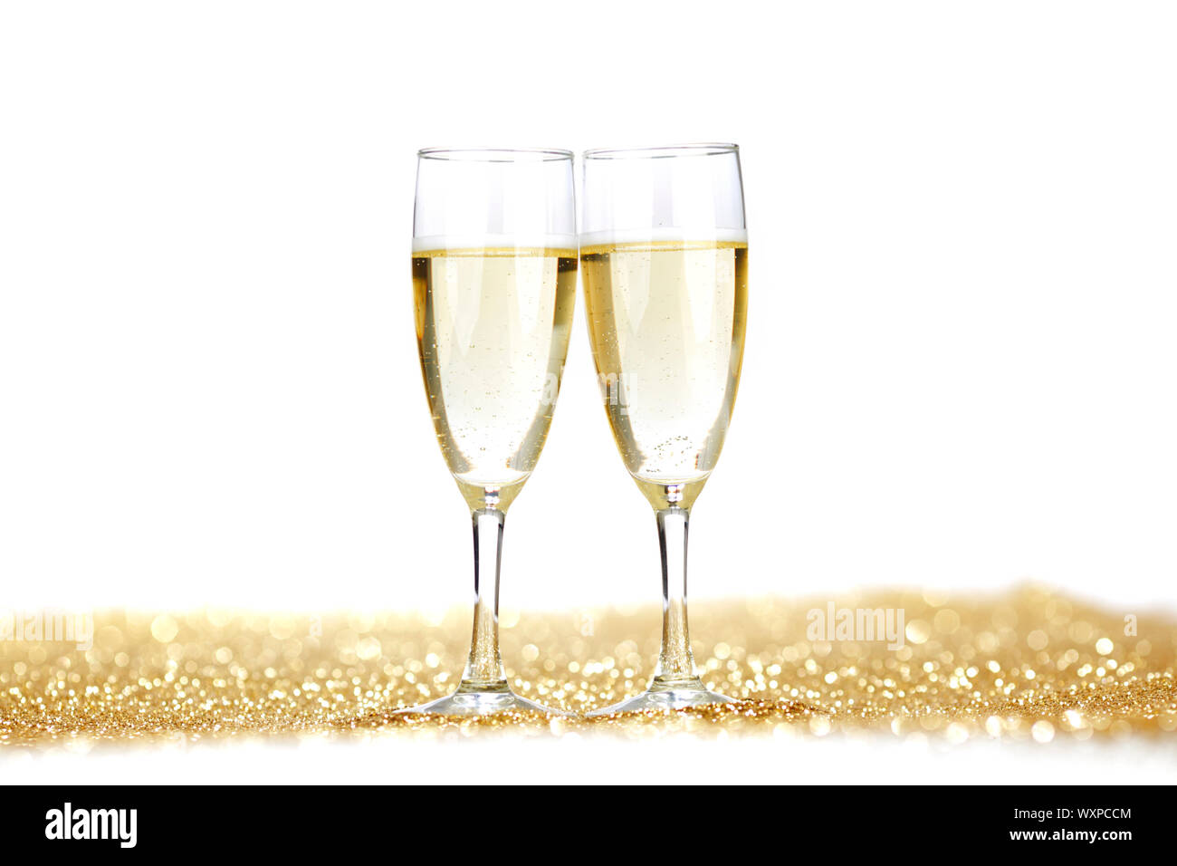 Two champagne flutes on gold shiny background Stock Photo - Alamy