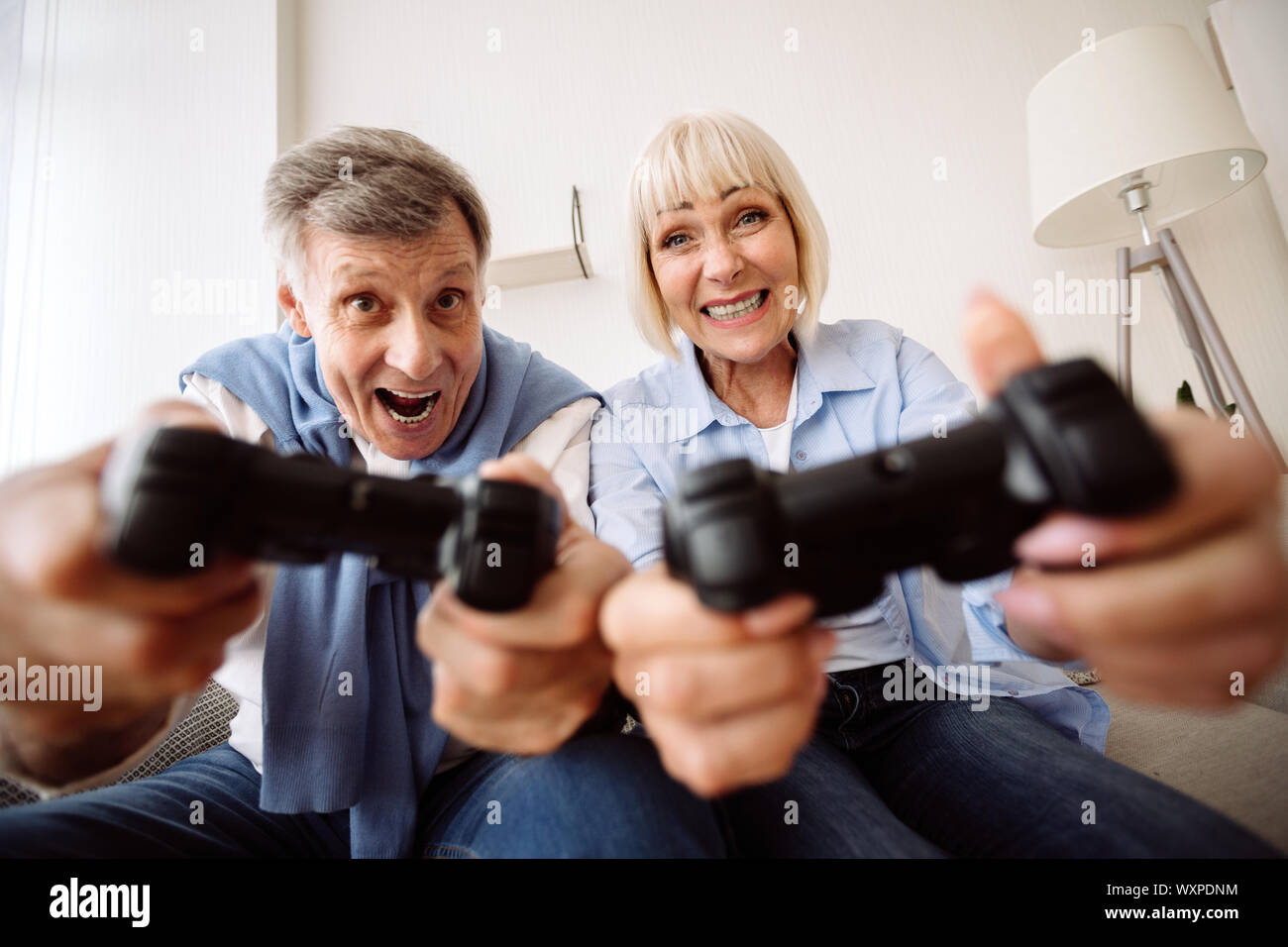 Excited mature couple playing video games at home Stock Photo