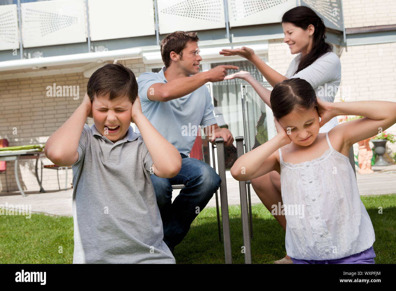 Little children covers their ears as their parents argue loudly behind Stock Photo Alamy