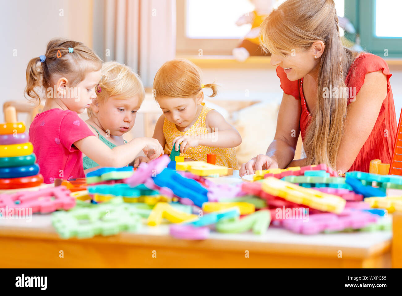 Group of children and teacher playing practical games in kindergarten Stock Photo