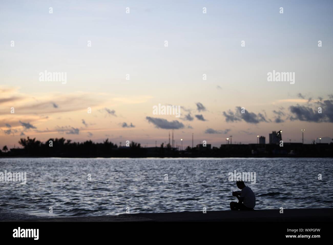 Nassau, Bahamas. 16th Sep, 2019. A man enjoys sunset on the beach days after Hurricane Dorian swept Nassau, capital of Bahamas, Sept. 16, 2019. Hurricane Dorian, a Category 5 storm, made a landfall on Elbow Cay in Abaco Islands in the Bahamas on Sept. 1. According to media reports, the list of missing as a result of Hurricane Dorian stands at an alarming 1,300 people and the death toll at 50. Credit: Xin Yuewei/Xinhua/Alamy Live News Stock Photo