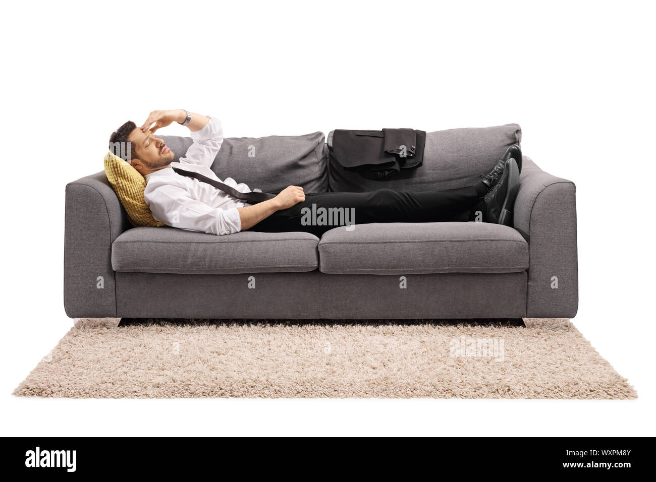 Full length shot of a businessman lying on a sofa bed after work and holding his head isolated on white background Stock Photo