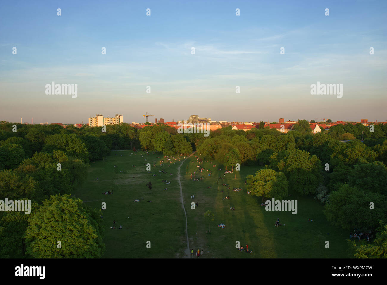 Aerial View of Berlin Park Hasenheide in Kreuzberg on an Spring afternoon with people relaxing and having fun on a large meadow in the sun. Behind the Stock Photo