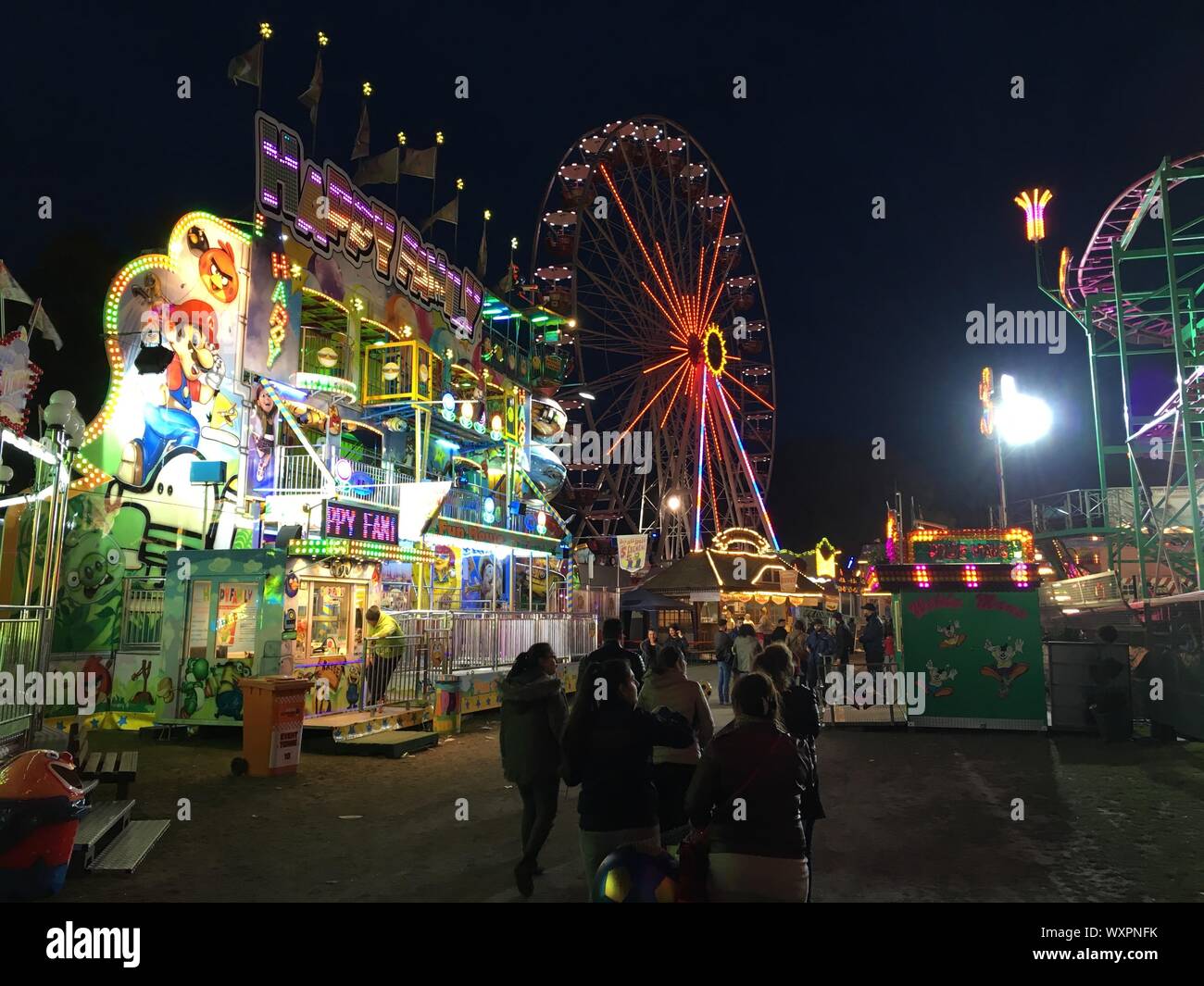 BERLIN - JUNE 3, 2017: Ferris Wheel, Fun House and Refreshment Stands at Night at German Fun Fair Stock Photo