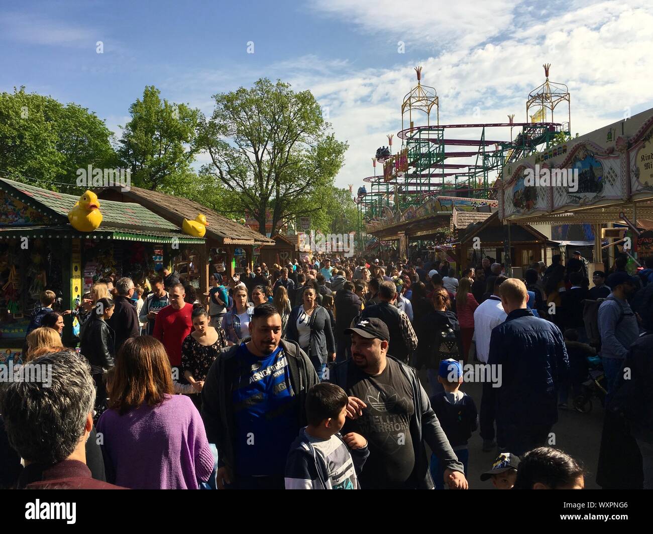 BERLIN - May 1, 2019: Crowded Fun Fair / Carnival with Roller Coaster in sunny spring weather (Kirmes) in Neukölln / Kreuzberg Stock Photo