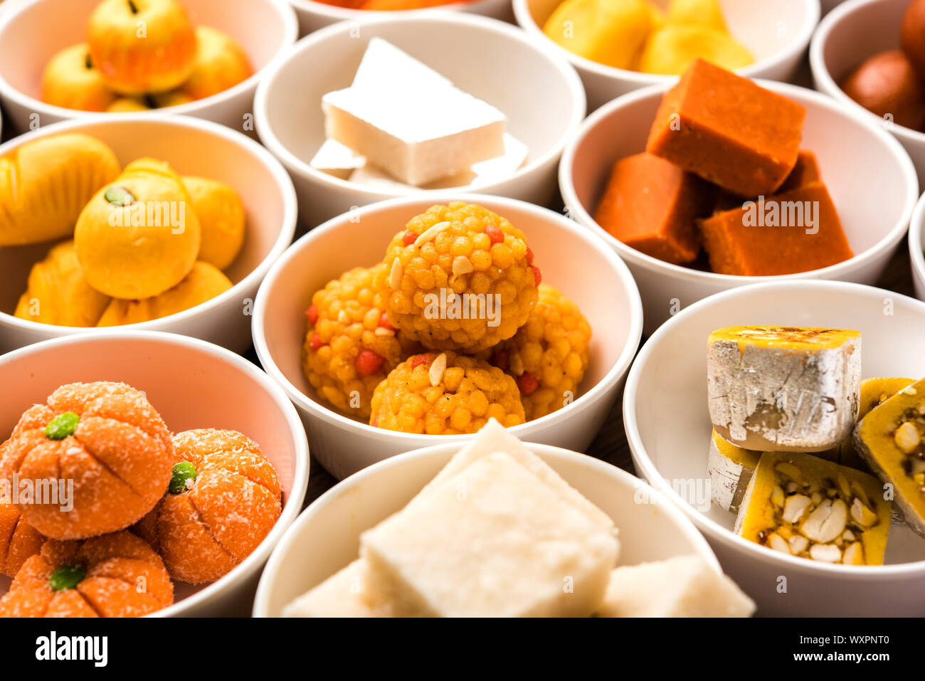 Rangoli of sweets and Farsan/snacks in bowls for Diwali with diya over