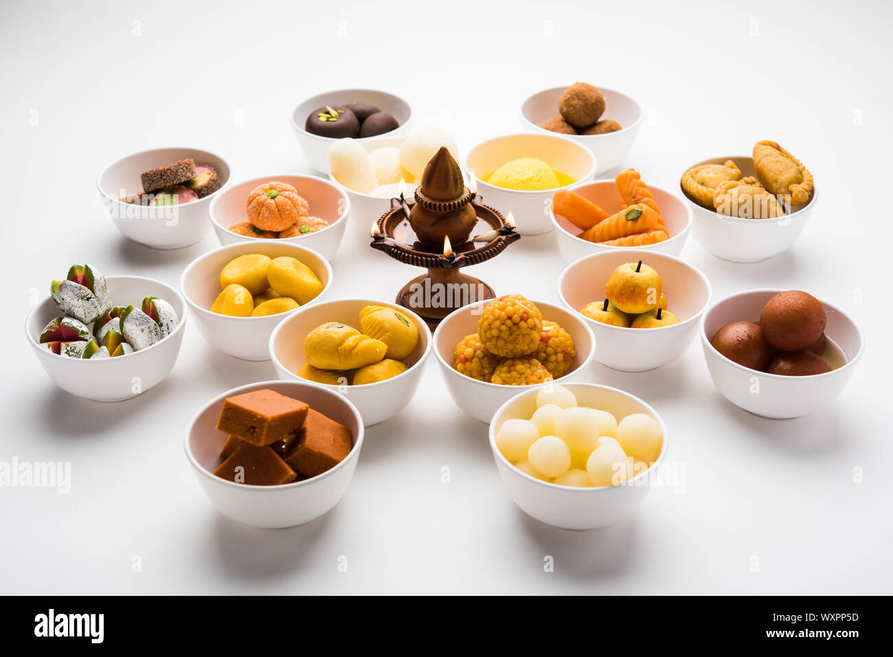 Snack Rangoli Rangoli of sweets and Farsan/snacks in bowls for Diwali with diya over ...