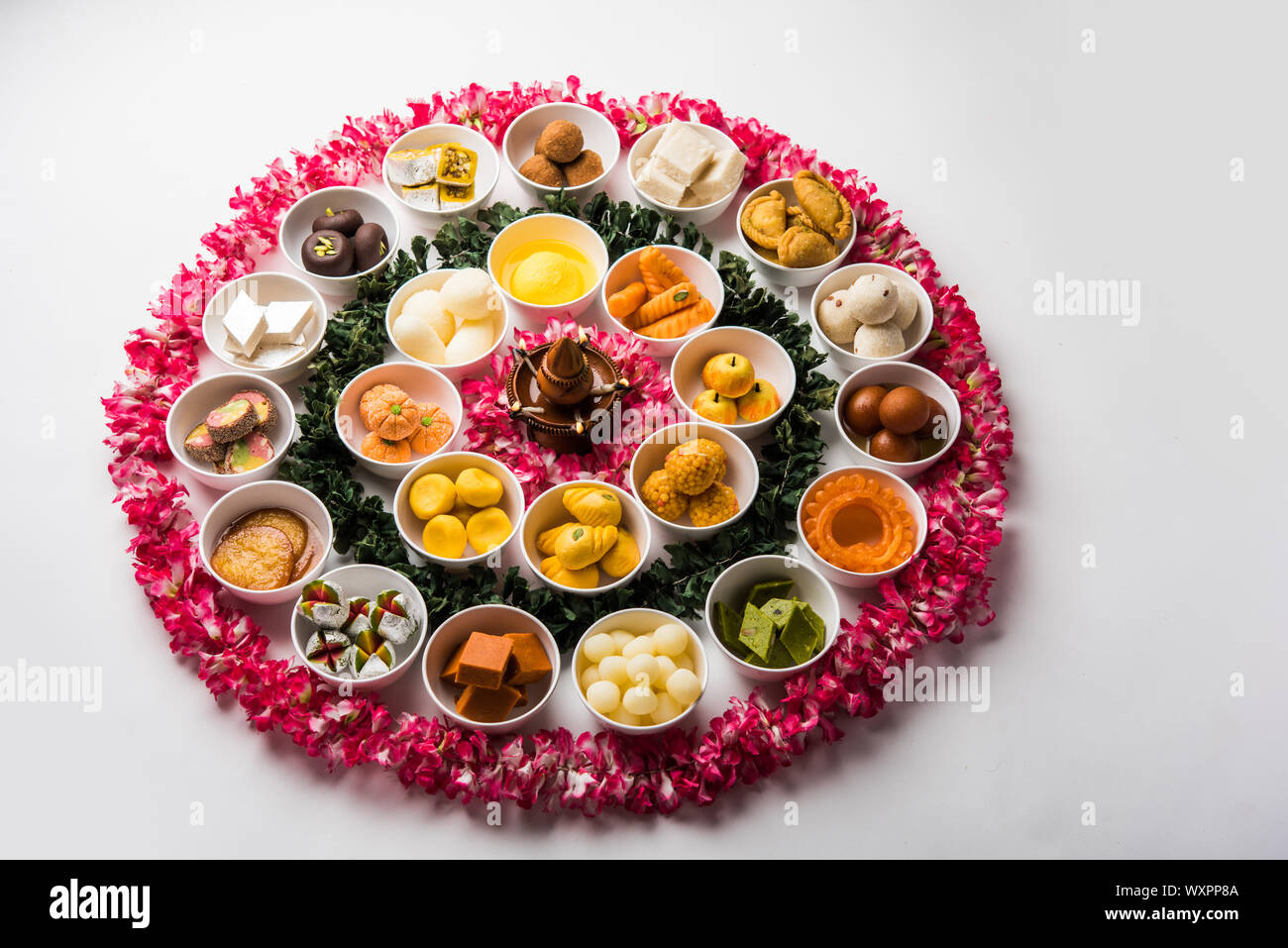 Snack Rangoli Rangoli of sweets and Farsan/snacks in bowls for Diwali with diya over ...