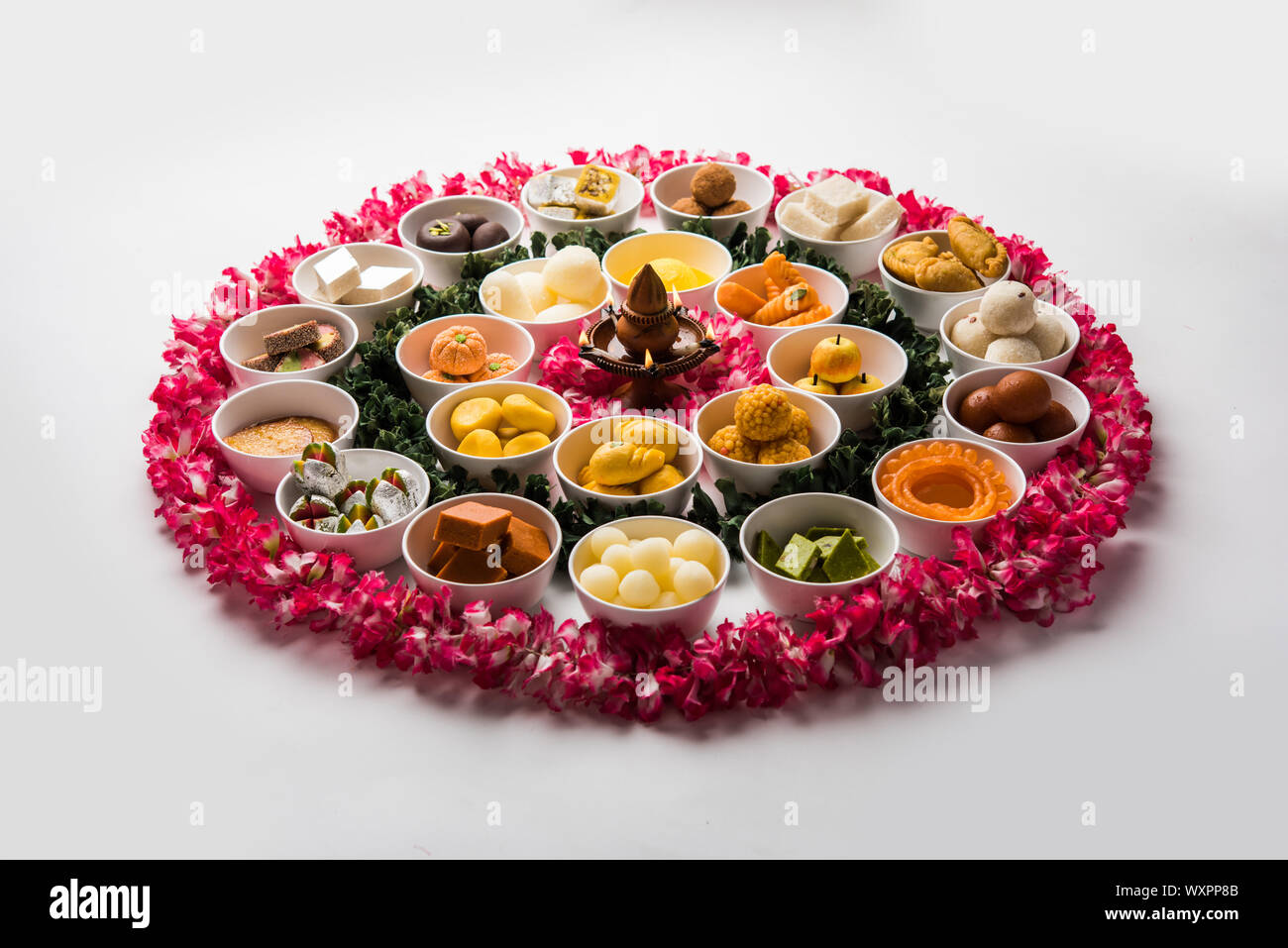 Rangoli of sweets and Farsan/snacks in bowls for Diwali with diya over