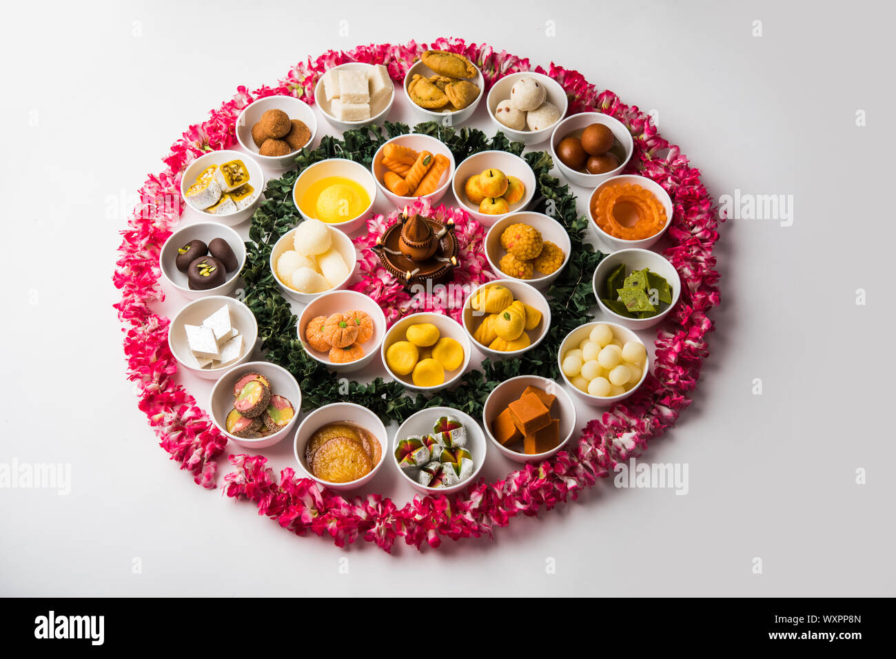 Snack Rangoli Rangoli of sweets and Farsan/snacks in bowls for Diwali with diya over ...