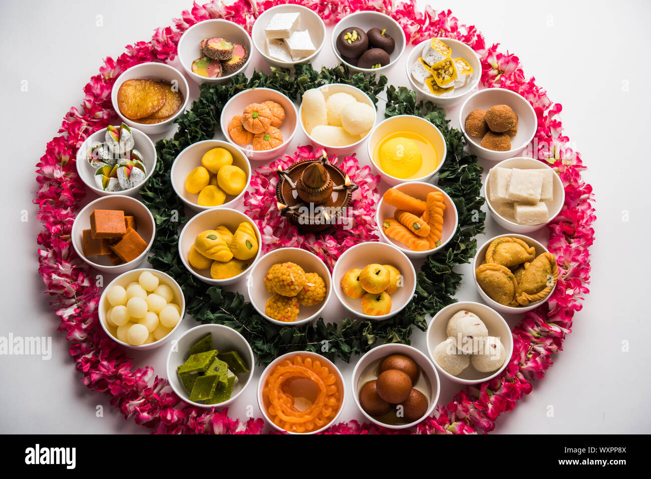 Snack Rangoli Rangoli of sweets and Farsan/snacks in bowls for Diwali with diya over ...