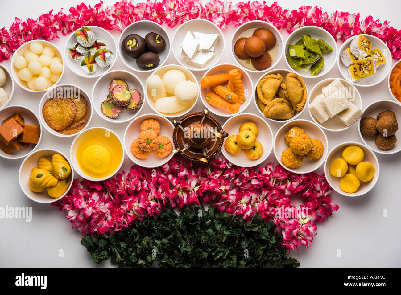 Rangoli of sweets and Farsan/snacks in bowls for Diwali with diya over ...