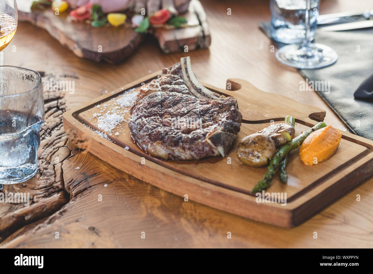 Grilled beef  chop served on wooden serving plate with  grilled vegetables Stock Photo