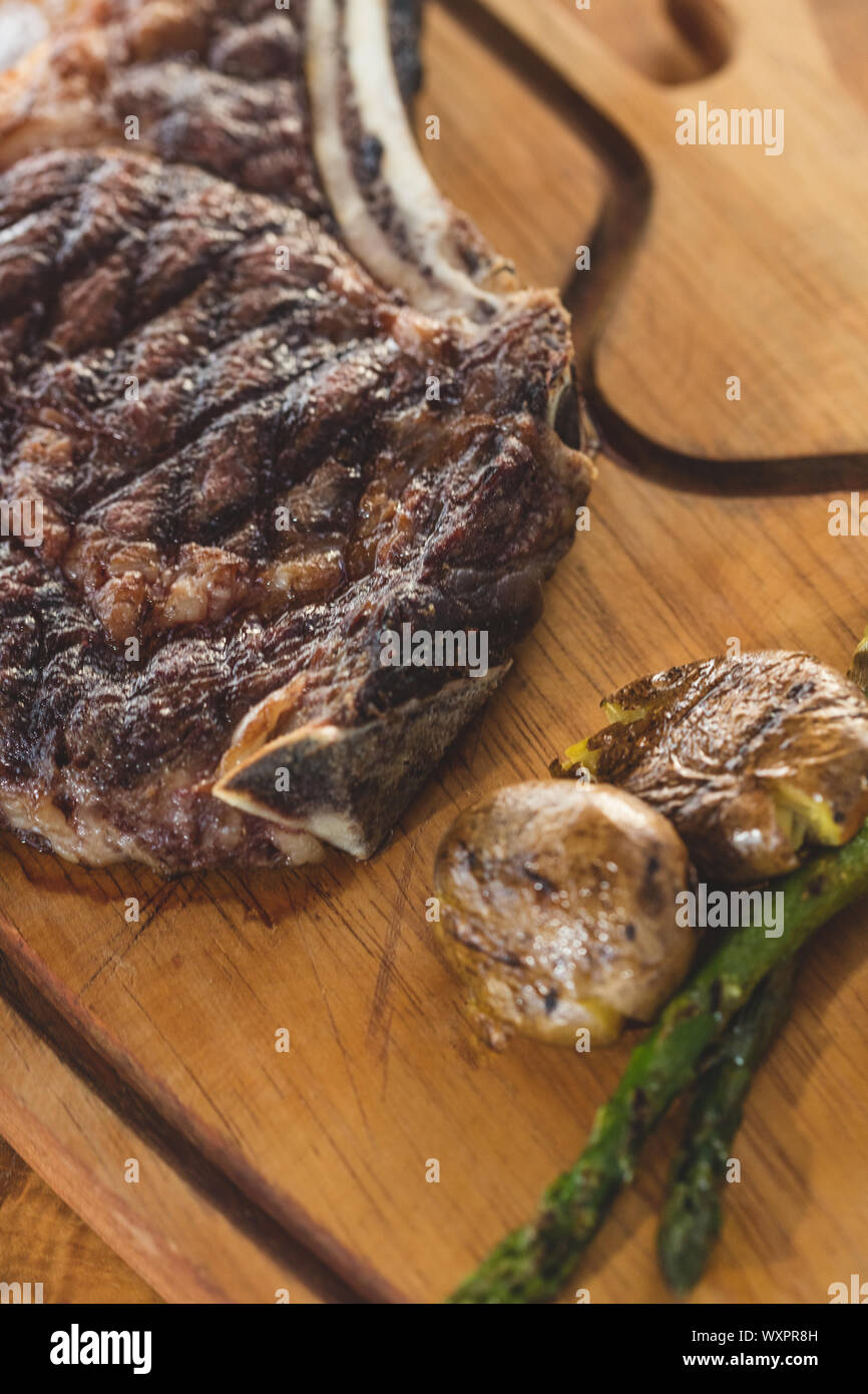 Grilled beef  chop served on wooden serving plate with  grilled vegetables Stock Photo