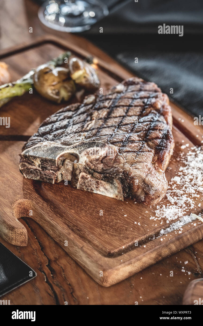 Barbecue beef t-bone  steak  served on wooden serving plate with grilled vegetables Stock Photo