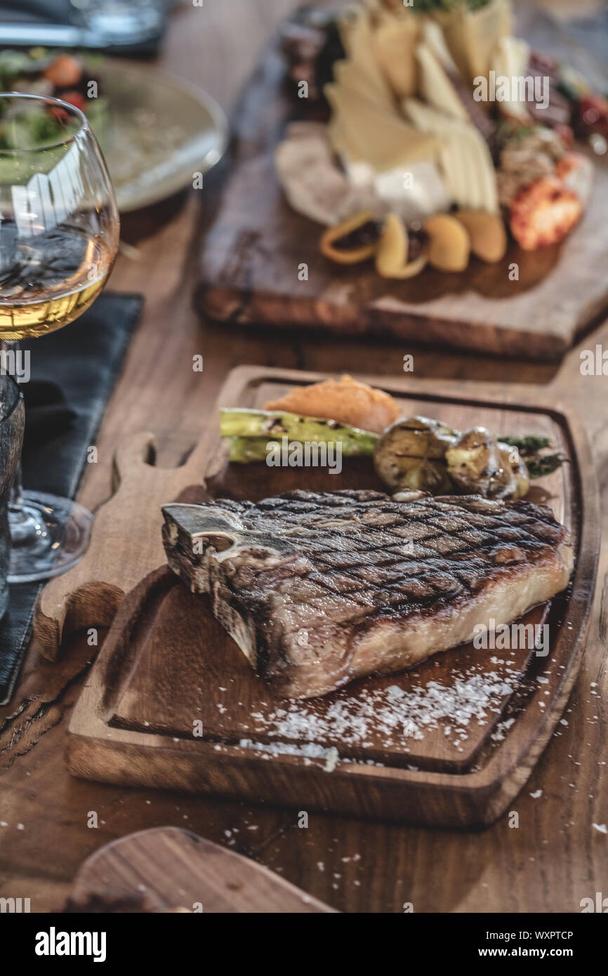 Barbecue beef t-bone  steak  served on wooden serving plate with wine and grilled vegetables Stock Photo