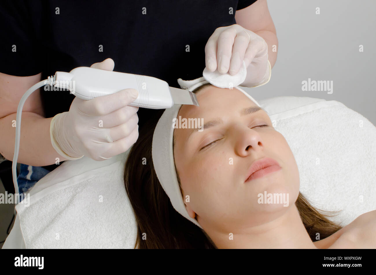 Beautiful woman receiving ultrasonic facial exfoliation procedure of