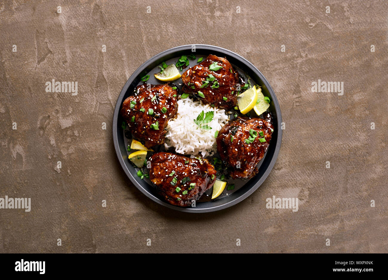 Honey soy sauce grilled chicken thighs with rice over dark stone