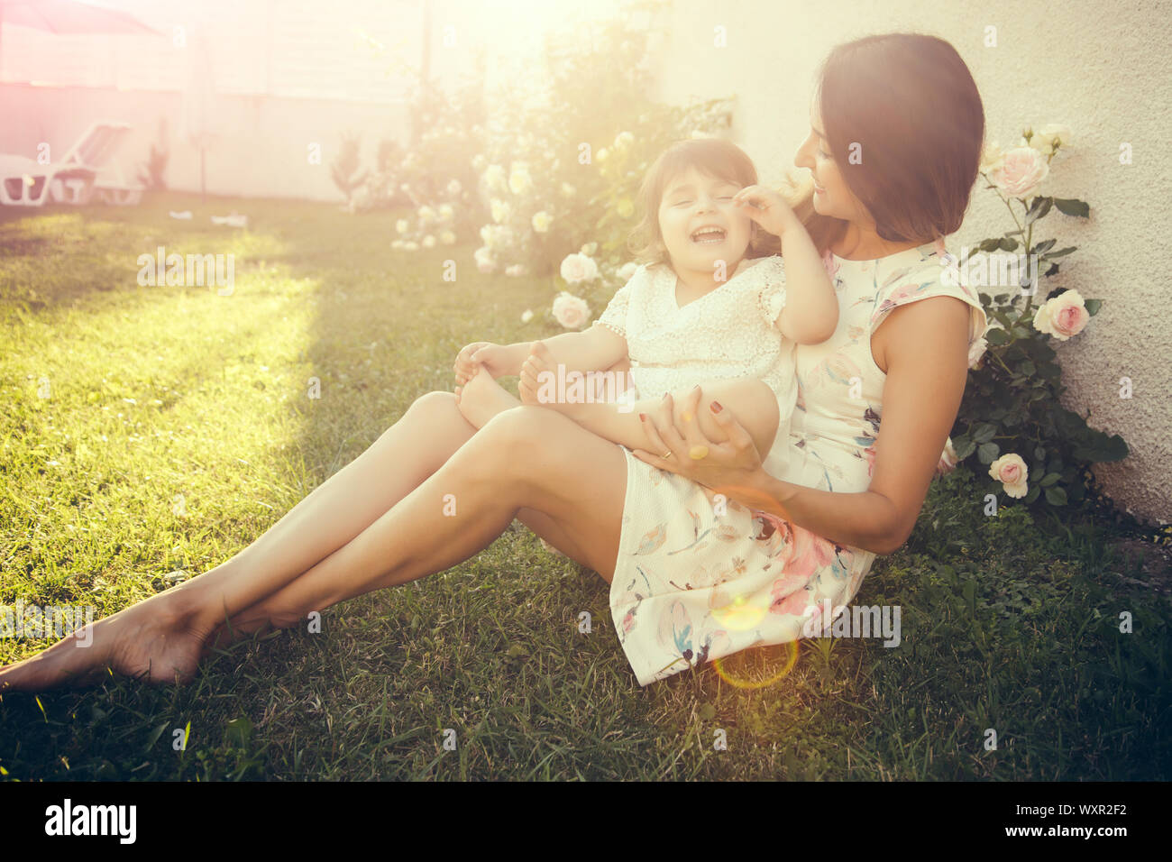 Mothers day concept. Mom and child smiling at blossoming rose flowers ...