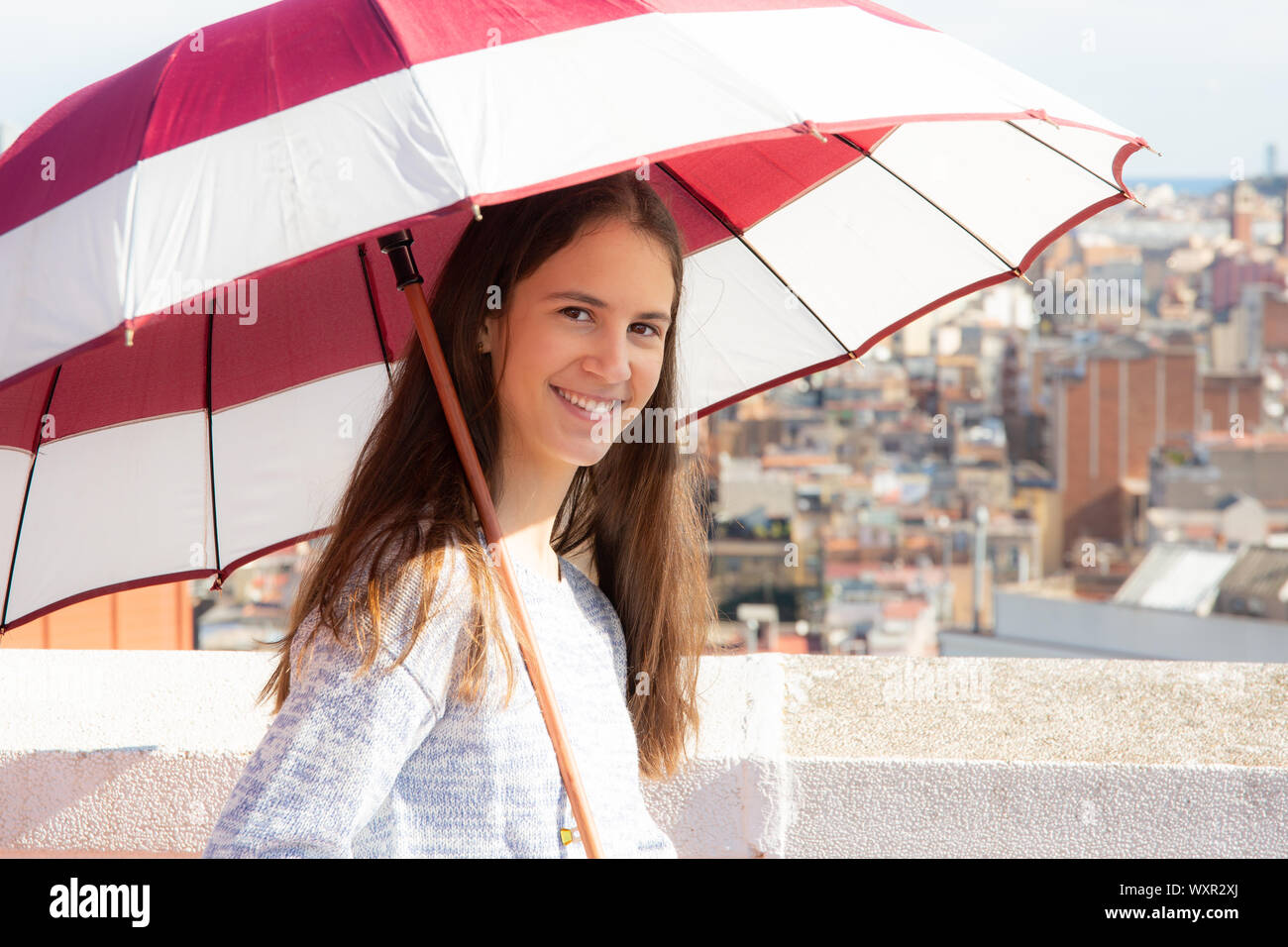 adolescente protegiéndose del sol con una sombrilla en la azotea Stock Photo -