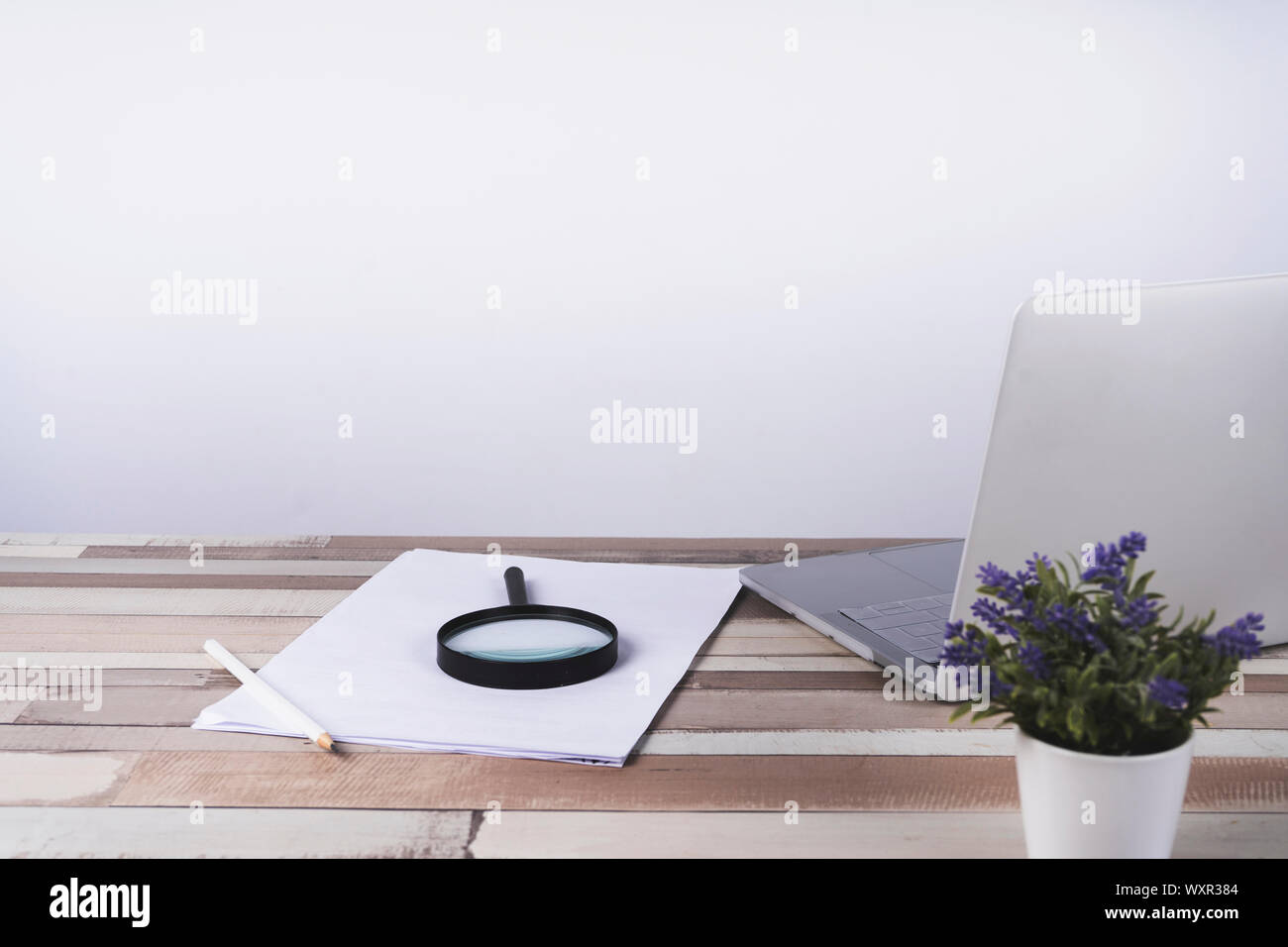 Wooden desk table with documents, a magnifying glass and laptop Stock Photo