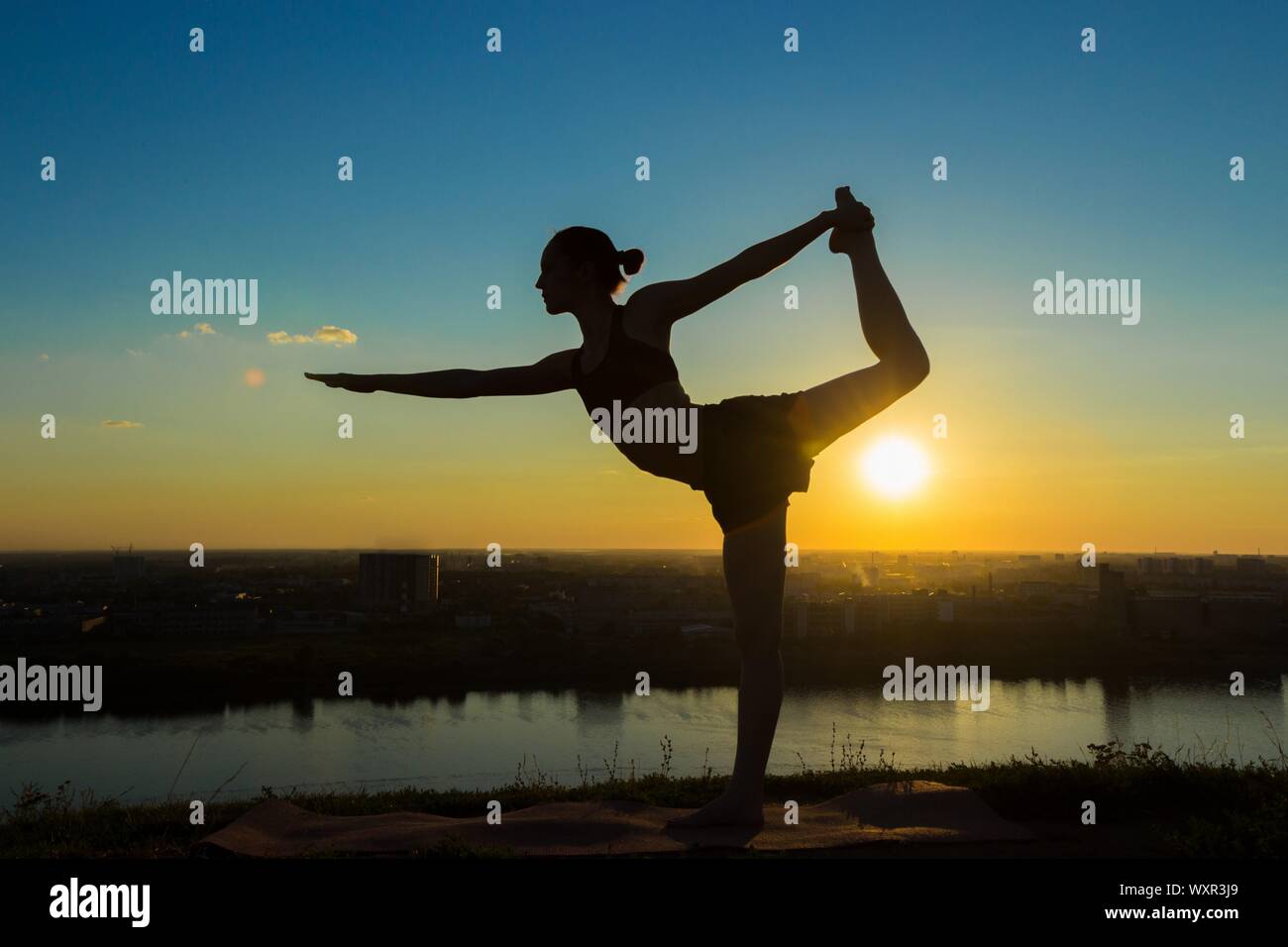Silhouette of sporty woman practicing yoga in the park at sunset - lord ...