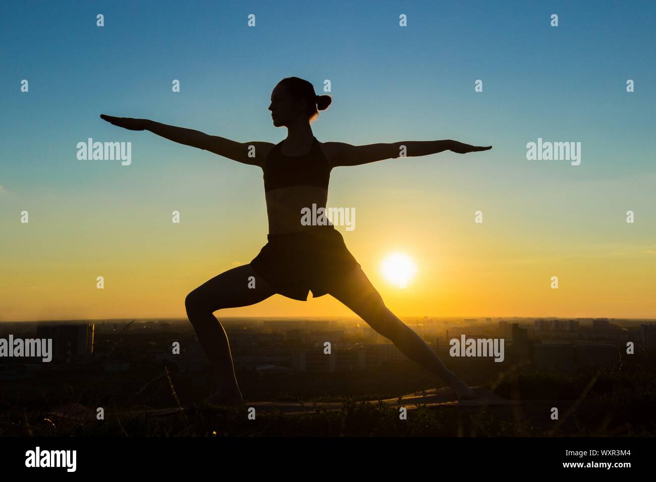 Silhouette of sporty woman doing Ashtanga yoga in the park at sunset ...
