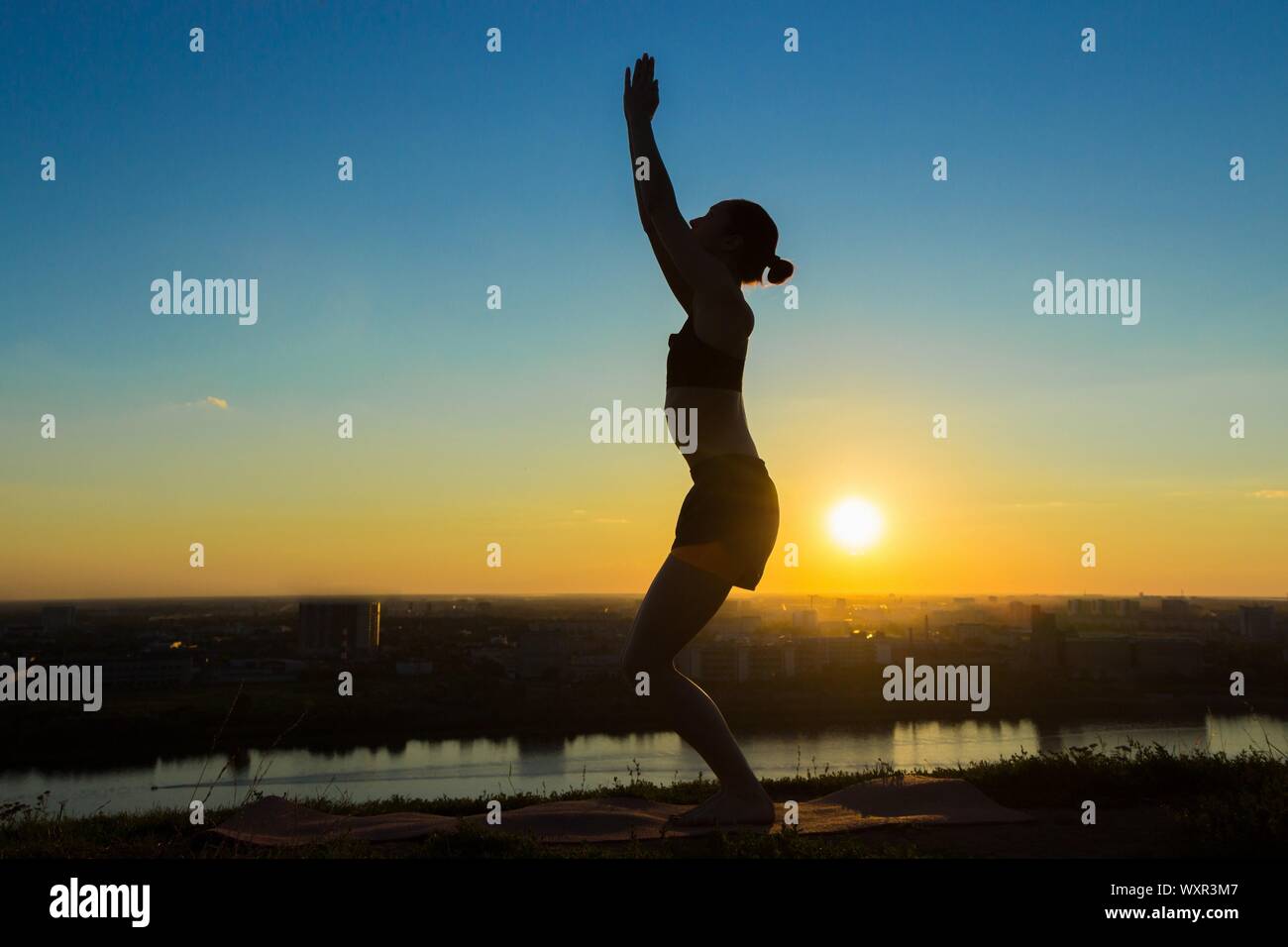 Silhouette of sporty woman practicing yoga in the park at sunset ...