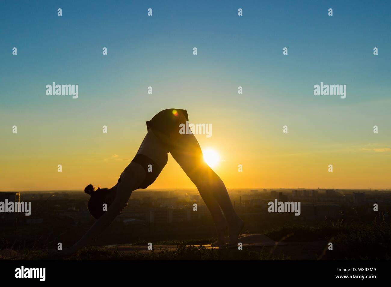 Silhouette of sporty woman doing Ashtanga yoga in the park at sunset ...