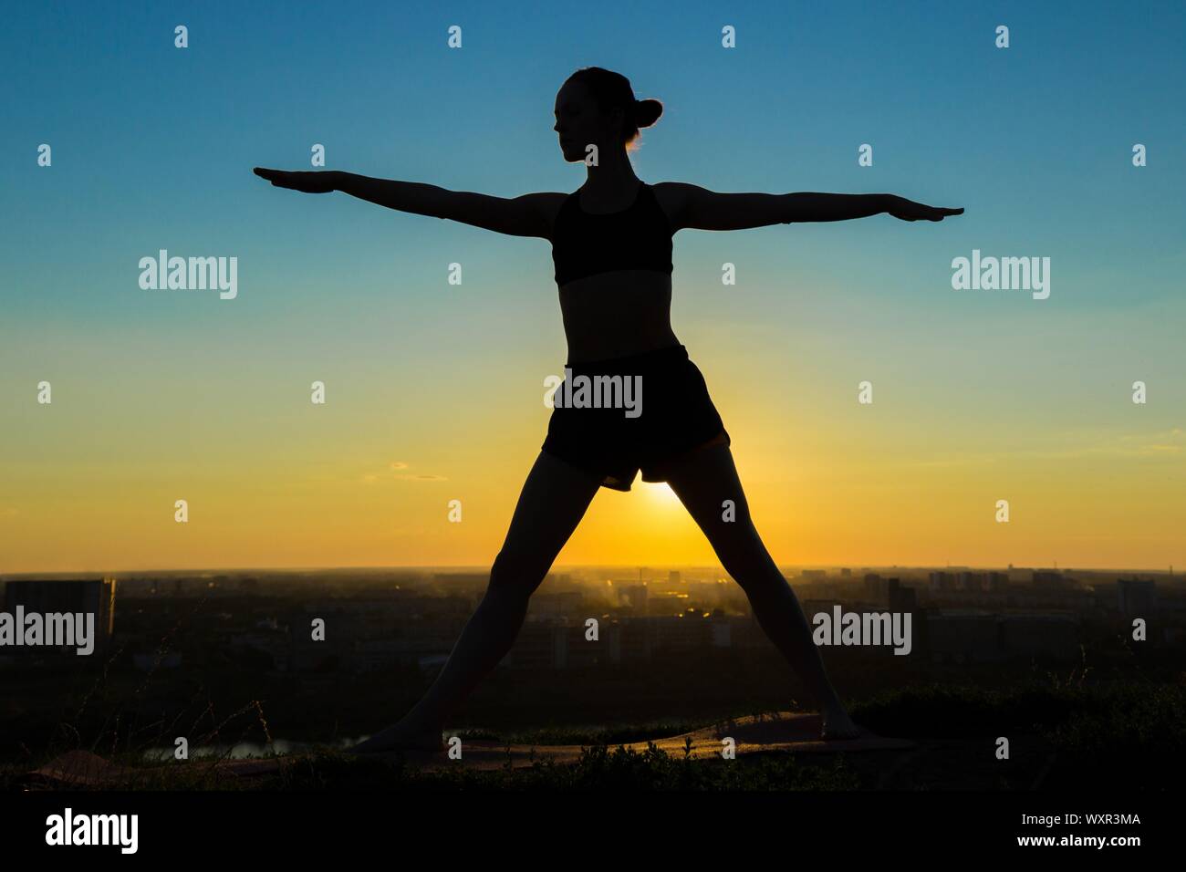 Silhouette of sporty woman doing Ashtanga yoga in the park at sunset ...
