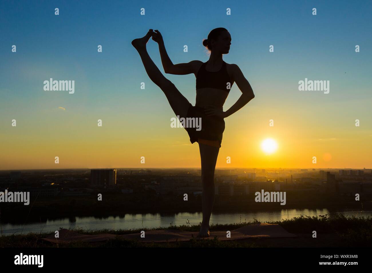 Silhouette of sporty woman practicing yoga in the park at sunset ...