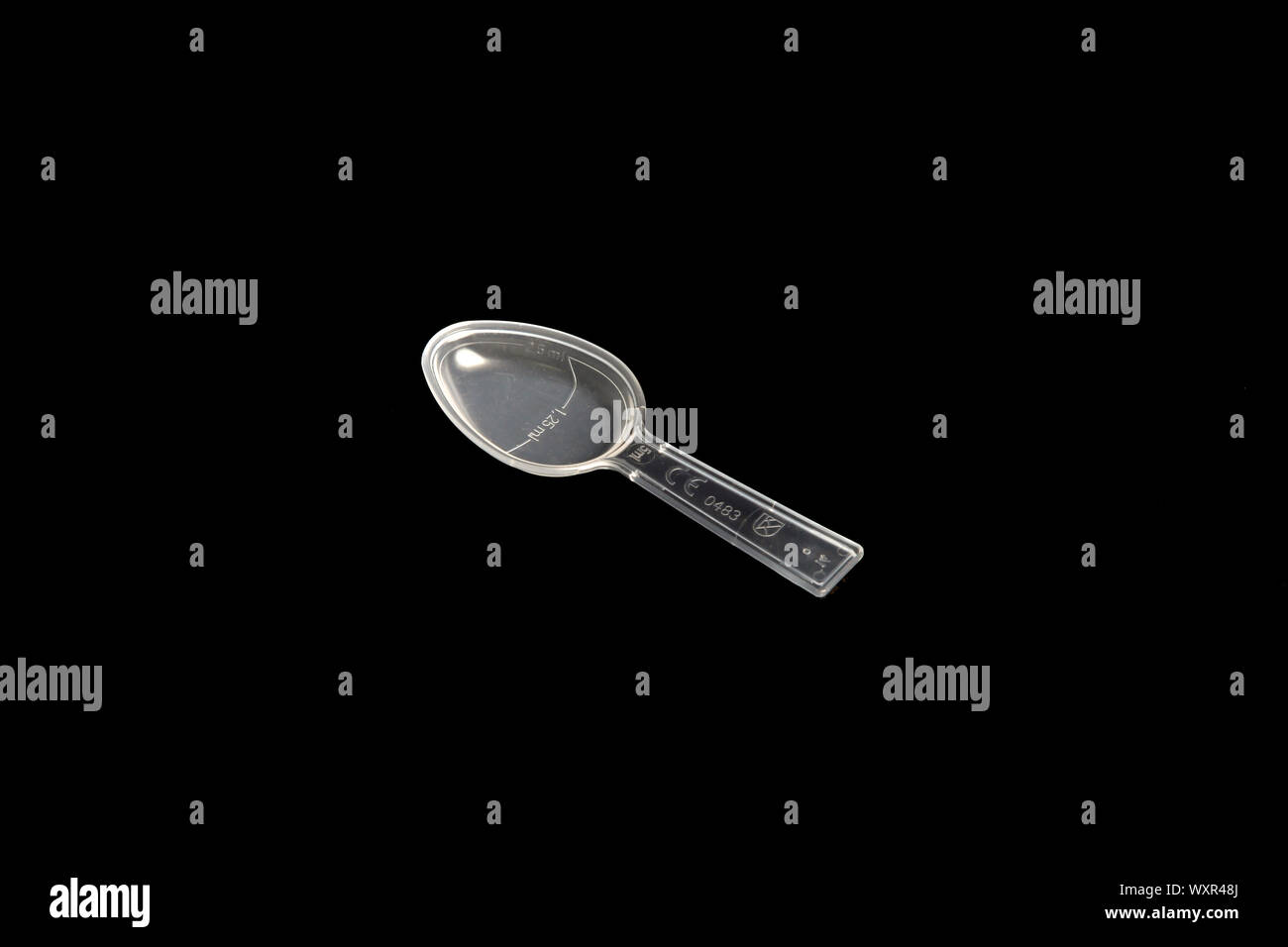 A single, clear, medicine dosage spoon isolated on black background Stock Photo