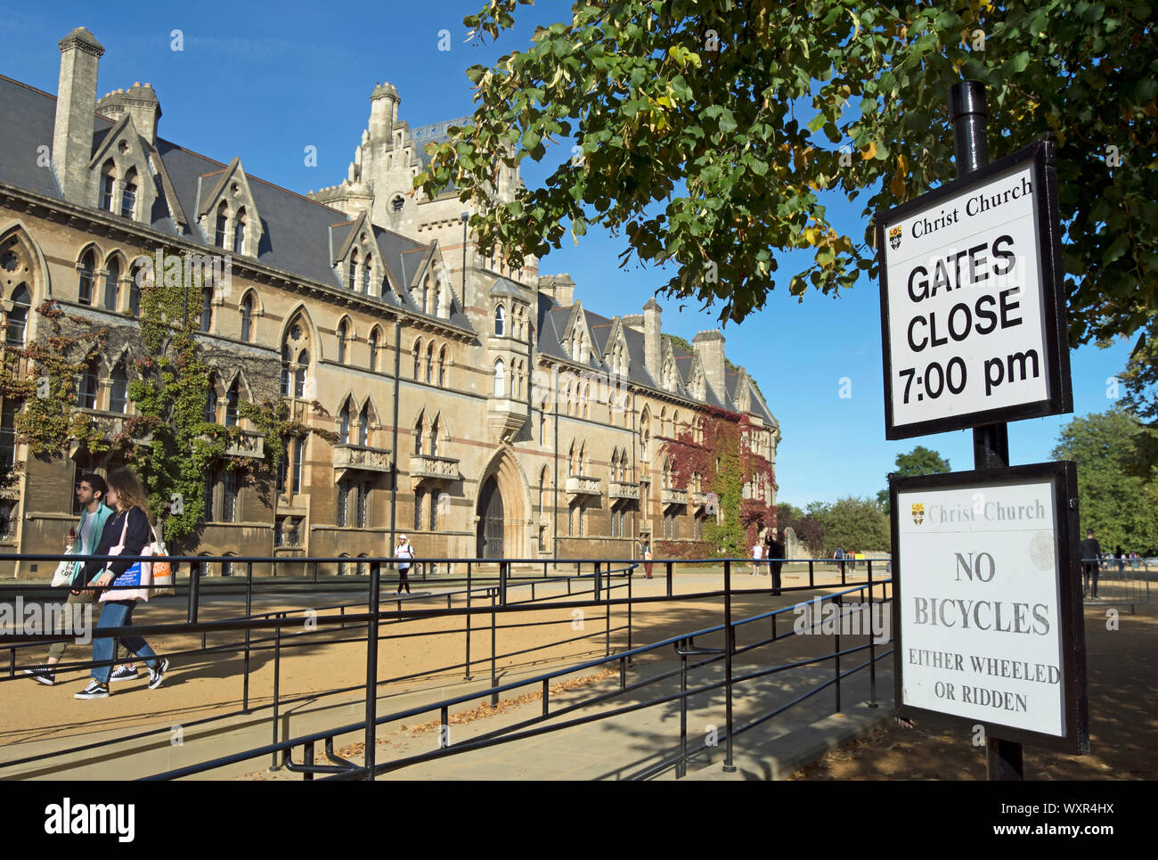 south side of the 1860s venetian gothic style meadow building, christ church college, oxford, england, with gate closure times and a no bicycles sign Stock Photo