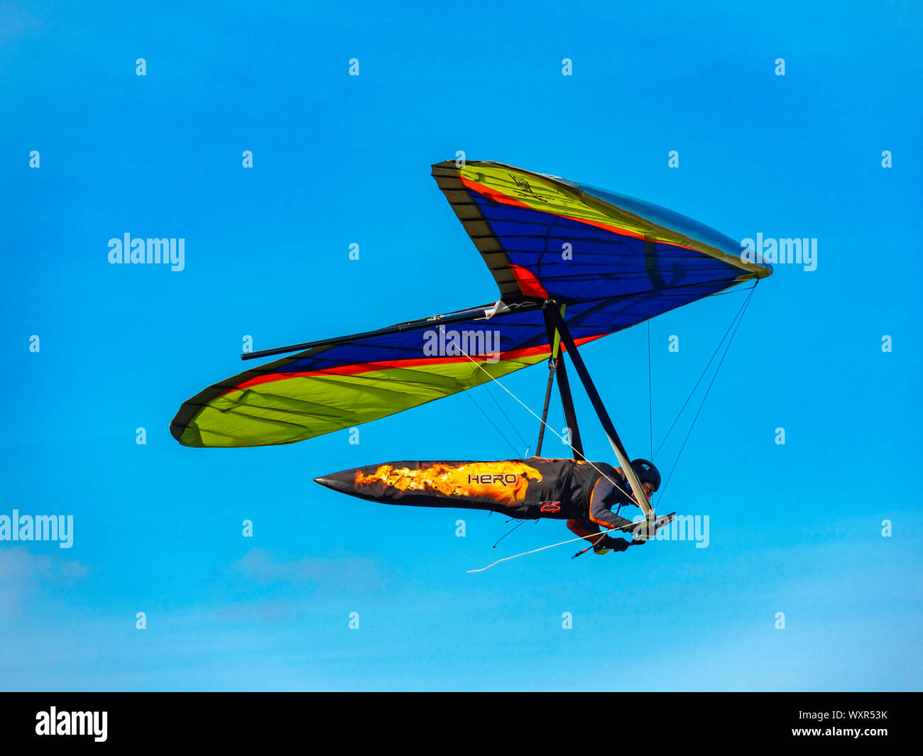 A blue yellow and red Moyes Hang Glider being flown at Carlton Bank on the Cleveland hills North Yorkshire Stock Photo