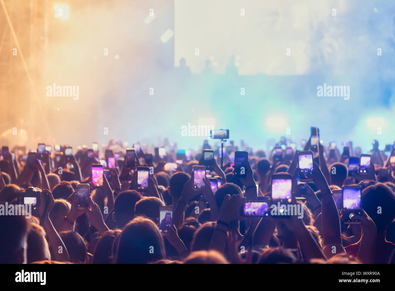 People taking photographs with touch smart phone during a music entertainment public concert.  live concert, music festival, happy youth, luxury party Stock Photo