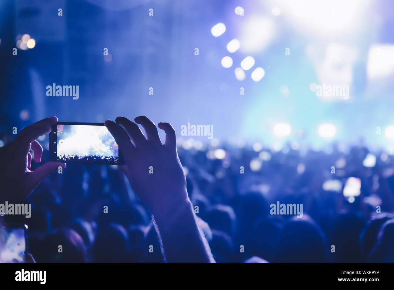People taking photographs with touch smart phone during a music entertainment public concert.  live concert, music festival, happy youth, luxury party Stock Photo