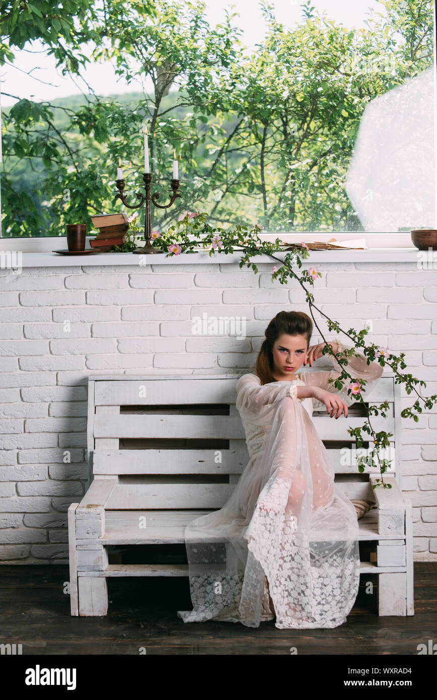 Beautiful young Parisian woman in long white silk dress sitting on the ...