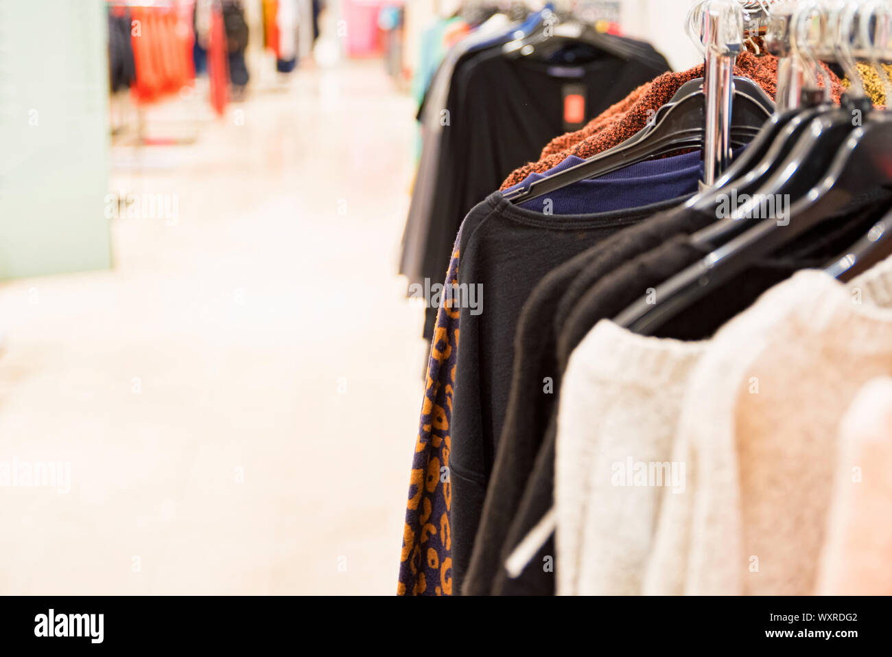 View of clothes shop interior with various clothes on hanging rail ...