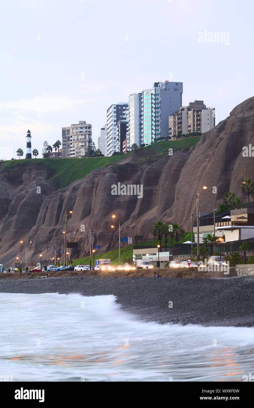 LIMA, PERU - APRIL 2, 2012: The steep coast and the lighthouse of the district of Miraflores as seen from the waterside in the evening in Lima, Peru Stock Photo