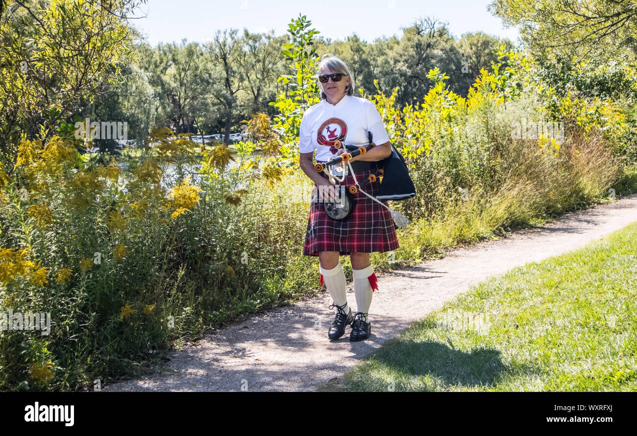 Lady dressed with a Scottish kilt, walks thru te park during the Dragon Boat Festival. Stock Photo