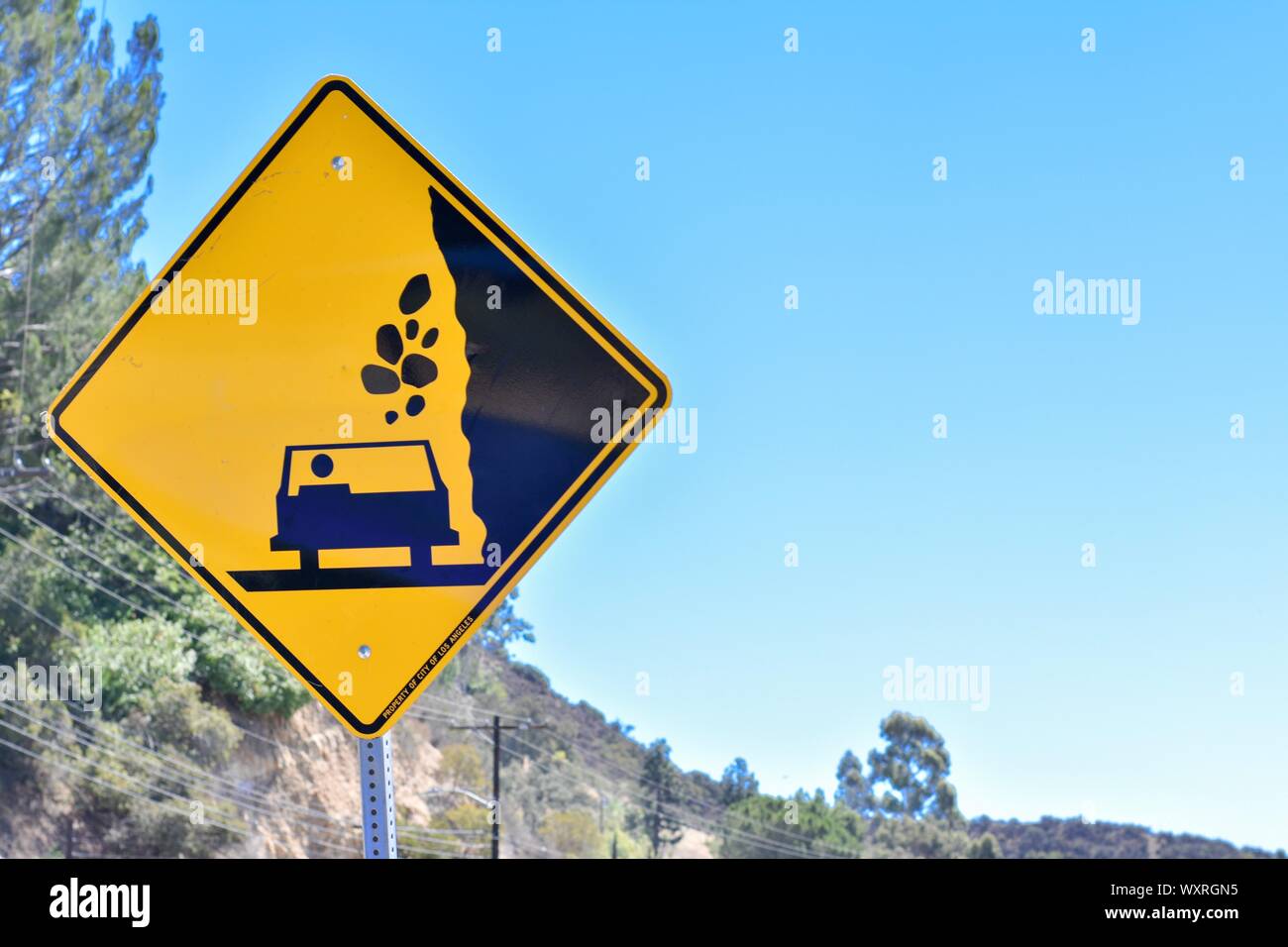 Beware of falling rocks on to car sign. Warning sign. Yellow and black