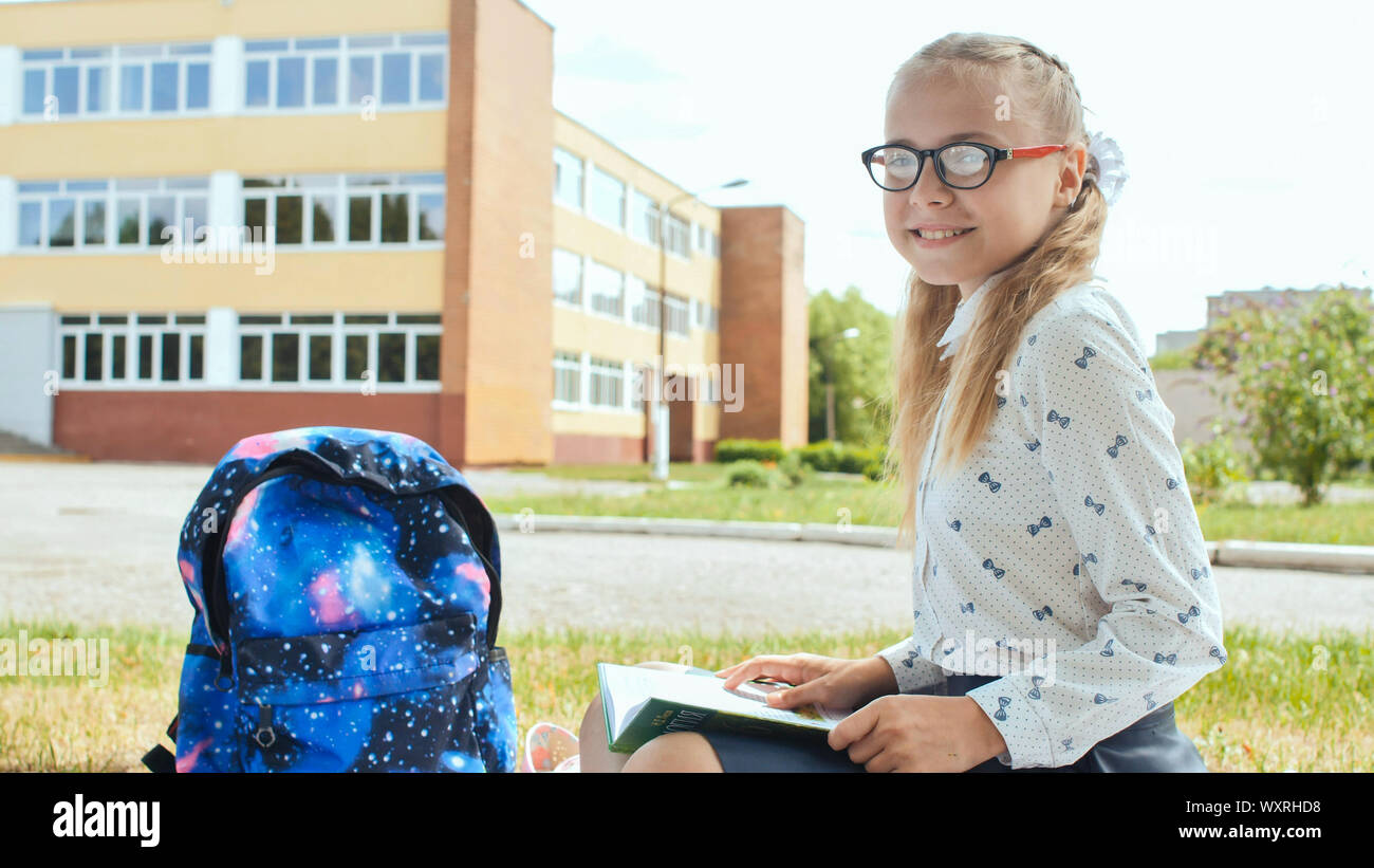 Porter of an 11 year old schoolgirl girl sitting on the background of her school. Stock Photo