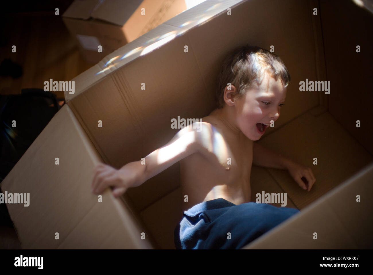 Young boy playing inside a box Stock Photo - Alamy