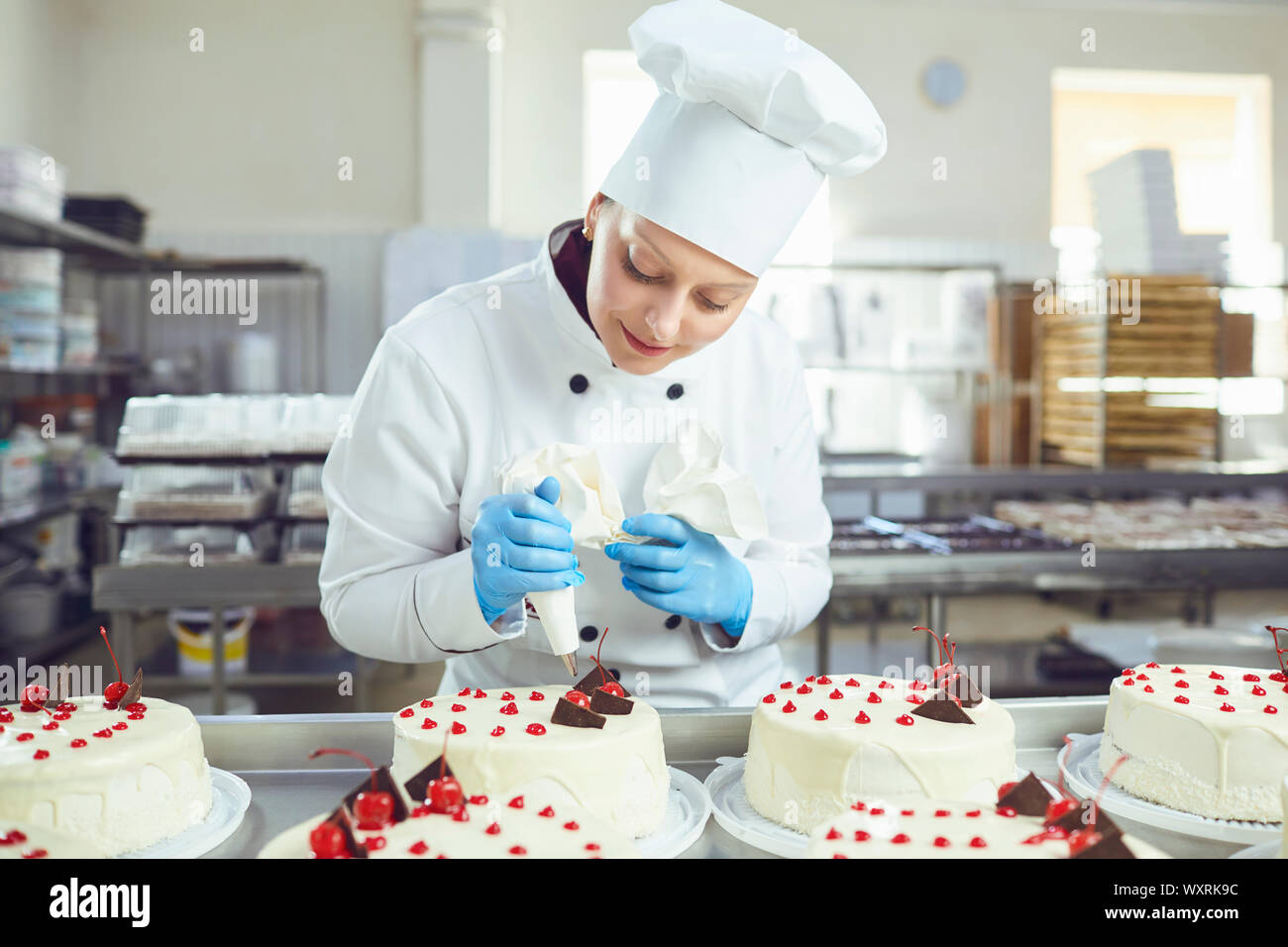 Confectioner with pastry cake in his hand at the bakery. Stock Photo